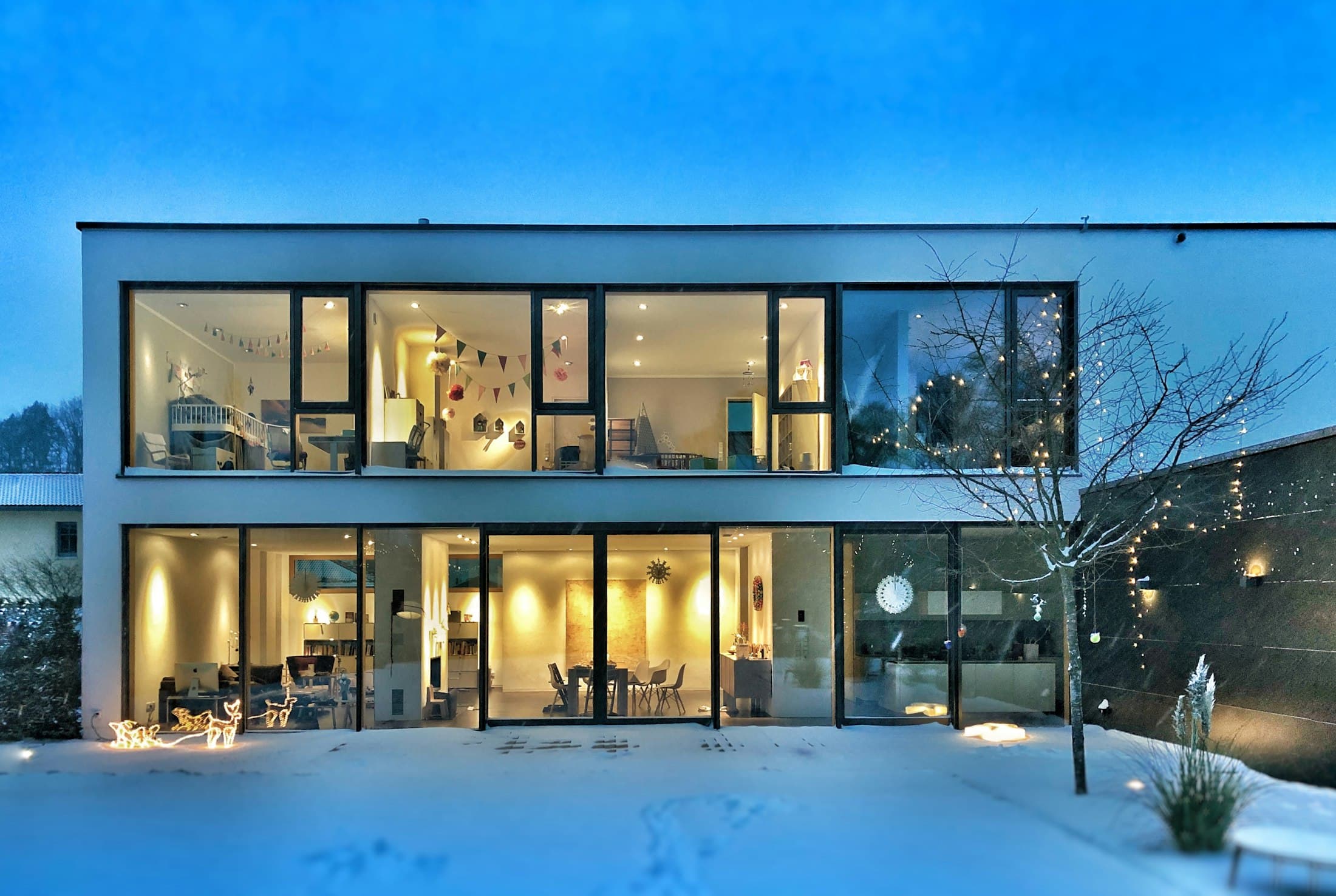 Glass-fronted modern home lit at dusk